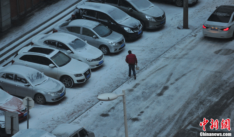 11月18日，行人在沈陽(yáng)街頭的積雪中穿行。