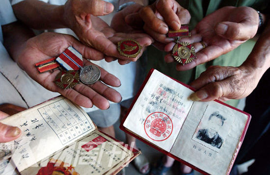 幾位志愿軍老兵展示自己的立功證、傷殘軍人證與勛章