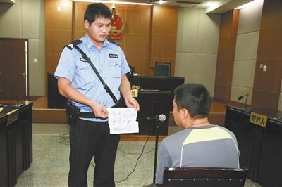昨日庭審中，法警向趙某出示其扎完車胎后所留辱罵公司的紙條。通訊員 李秀文 攝