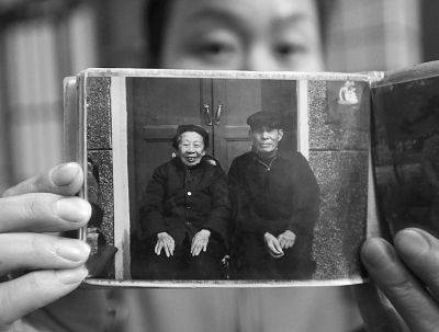 圖為孫女拿出兩位老人上世紀(jì)80年代在家門口的合影給記者看。記者楊濤 攝