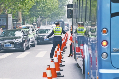 省人民醫(yī)院南門的路中間擺放反光錐，交警示意由西向東車輛從前方繞行。