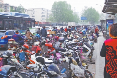省人民醫(yī)院北門，路邊的公交站牌處停滿非機動車，上、下客只能在快車道上。