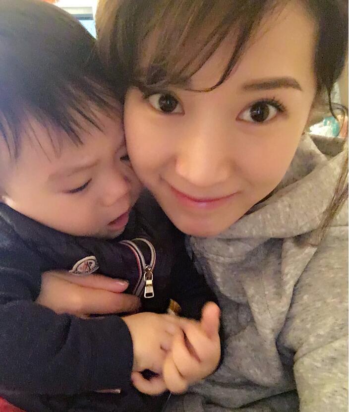 照片中李念狂吻兒子，小寶貝自顧自地玩著。