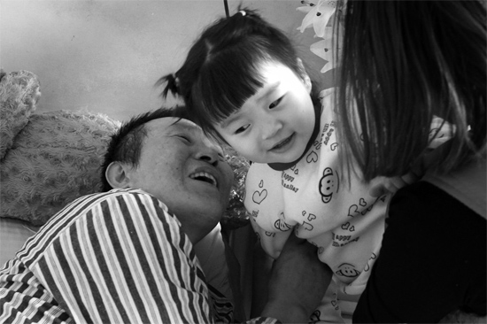 病床前李剛父女倆說著“悄悄話”，幸福的氣氛洋溢在病房中