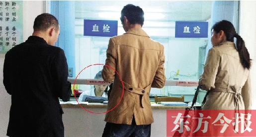 昨日，鄭州市二七區(qū)疾控中心辦證大廳，血檢窗口內(nèi)一名女工作人員，邊接受辦證者咨詢邊看報(bào)紙