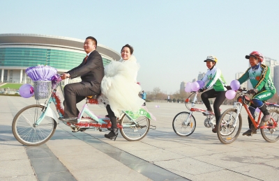 氣球和鮮花裝點(diǎn)的雙人自行車，新郎郝幸福載著美麗新娘回家。